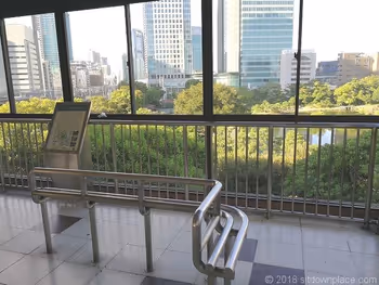浜松町駅歩行者通路のベンチと旧芝離宮恩賜庭園の景観